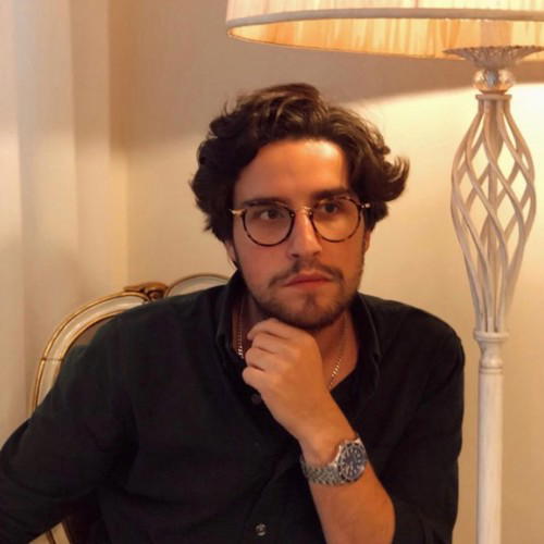 André Cardoso - A man with glasses and a dark shirt sits in a chair.