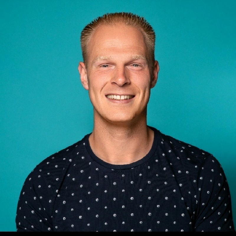 Lars Maat - Smiling man in a dotted shirt against a blue background.